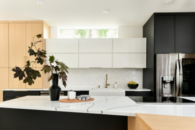 Eat-in kitchen - large contemporary single-wall medium tone wood floor and yellow floor eat-in kitchen idea in Seattle with a farmhouse sink, shaker cabinets, black cabinets, quartz countertops, white backsplash, porcelain backsplash, stainless steel appliances, an island and white countertops