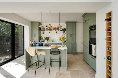 Medium sized victorian galley open plan kitchen in Other with a built-in sink, beaded cabinets, green cabinets, quartz worktops, white splashback, ceramic splashback, black appliances, porcelain flooring, an island, beige floors and white worktops.