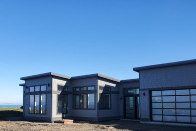 Large trendy gray one-story concrete fiberboard and shingle house exterior photo in Seattle with a shed roof, a metal roof and a black roof