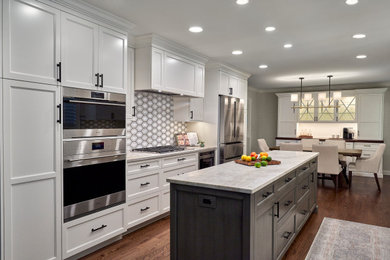 Eat-in kitchen - large traditional galley medium tone wood floor and brown floor eat-in kitchen idea in Chicago with an undermount sink, recessed-panel cabinets, gray cabinets, quartzite countertops, brown backsplash, stone tile backsplash, stainless steel appliances, an island and beige countertops