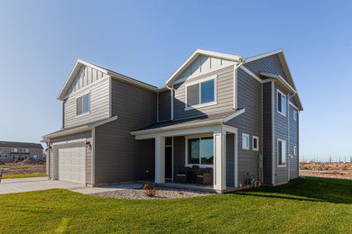 This is an example of a large transitional two-storey grey house exterior in Other with concrete fiberboard siding, a gable roof and a shingle roof.
