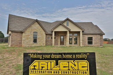 Example of an arts and crafts beige two-story stone exterior home design in Dallas with a hip roof