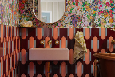 Example of an eclectic 3/4 pink tile and ceramic tile ceramic tile, red floor, single-sink and wallpaper claw-foot bathtub design in Los Angeles with pink cabinets, a wall-mount sink, concrete countertops, pink countertops and a floating vanity