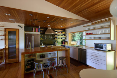 Mid-sized 1960s l-shaped light wood floor, brown floor and wood ceiling eat-in kitchen photo in Portland with an undermount sink, flat-panel cabinets, white cabinets, quartz countertops, metallic backsplash, stainless steel appliances, an island and white countertops