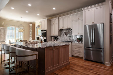 Example of a large classic galley medium tone wood floor and brown floor open concept kitchen design in Nashville with an undermount sink, beaded inset cabinets, white cabinets, granite countertops, white backsplash, granite backsplash, stainless steel appliances, an island and white countertops