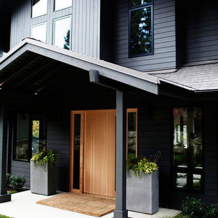 Новый формат декора квартиры: большой, двухэтажный фасад дома серого цвета в современном стиле с облицовкой из дерева и мансардной крышей