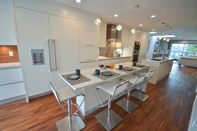 Inspiration for a large modern single-wall dark wood floor and brown floor enclosed kitchen remodel in Vancouver with an undermount sink, flat-panel cabinets, white cabinets, quartz countertops, metallic backsplash, metal backsplash, paneled appliances and two islands