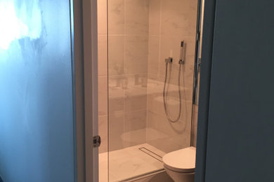 This is an example of a mid-sized modern master bathroom in Melbourne with an open shower, a two-piece toilet, white tile, porcelain tile, a wall-mount sink, granite benchtops, an open shower, a single vanity and a floating vanity.