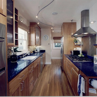 Mid-sized modern galley kitchen pantry in Sacramento with a drop-in sink, recessed-panel cabinets, medium wood cabinets, stainless steel appliances, medium hardwood floors, no island, quartz benchtops, metallic splashback, metal splashback and blue benchtop.