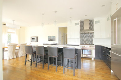 Example of a mid-sized trendy l-shaped medium tone wood floor open concept kitchen design in Ottawa with a single-bowl sink, recessed-panel cabinets, black cabinets, quartz countertops, gray backsplash, stainless steel appliances and an island