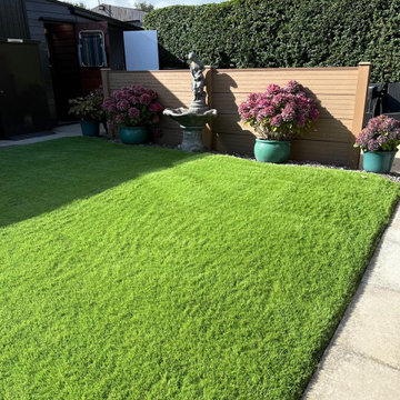Artificial Lawn With Composite Fencing and a Stone Fountain