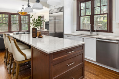 Inspiration for a mid-sized transitional galley medium tone wood floor and brown floor eat-in kitchen remodel in Detroit with an undermount sink, recessed-panel cabinets, white cabinets, quartz countertops, beige backsplash, ceramic backsplash, stainless steel appliances, an island and beige countertops