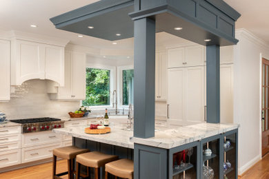 Kitchen - mid-sized transitional l-shaped medium tone wood floor and brown floor kitchen idea in Other with raised-panel cabinets, blue cabinets, marble countertops, white backsplash, ceramic backsplash, paneled appliances, an island and white countertops