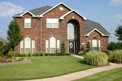 Photo of a large contemporary two-storey brick red house exterior in Dallas with a gable roof and a shingle roof.
