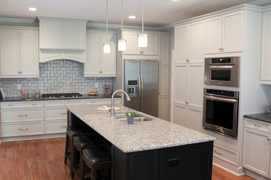 Example of a mid-sized classic u-shaped dark wood floor eat-in kitchen design in Raleigh with an undermount sink, recessed-panel cabinets, gray cabinets, granite countertops, gray backsplash, ceramic backsplash, stainless steel appliances and an island