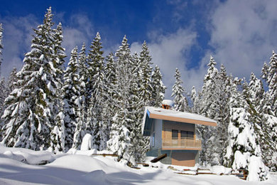 Cette photo montre une petite façade de maison montagne en bois à trois étages et plus avec un toit à deux pans, un toit en tuile et un toit gris.