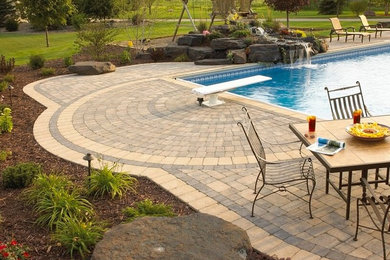 Design ideas for a mid-sized traditional backyard round lap pool in Minneapolis with a water feature and concrete pavers.