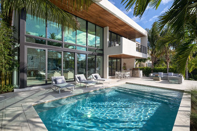 Patio - large contemporary backyard stone patio idea in Miami with a roof extension