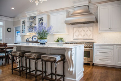 Mid-sized elegant l-shaped eat-in kitchen photo in Cleveland with recessed-panel cabinets, white cabinets, marble countertops, beige backsplash, paneled appliances and an island