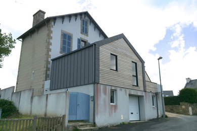 Aménagement d'une façade de maison grise de taille moyenne et à un étage avec un revêtement mixte et un toit à deux pans.
