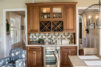 Mid-sized transitional single-wall beige floor home bar photo in Detroit with raised-panel cabinets, medium tone wood cabinets, quartz countertops, gray backsplash and white countertops