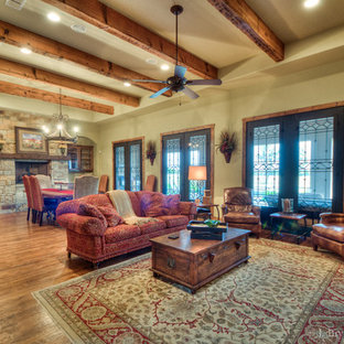 Großes, Offenes Mediterranes Wohnzimmer mit beiger Wandfarbe, Teppichboden, Kamin, Kaminsims aus Stein und verstecktem TV in Austin