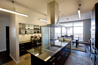 Mid-sized trendy l-shaped slate floor and brown floor eat-in kitchen photo in Other with a farmhouse sink, flat-panel cabinets, dark wood cabinets, granite countertops, white backsplash, glass tile backsplash, stainless steel appliances and an island