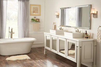 Photo of an expansive transitional master bathroom in Indianapolis with glass-front cabinets, beige cabinets, a freestanding tub, beige walls, medium hardwood floors, a vessel sink and brown floor.