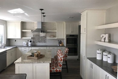 Eat-in kitchen - large transitional u-shaped dark wood floor and brown floor eat-in kitchen idea in San Diego with a double-bowl sink, shaker cabinets, white cabinets, granite countertops, beige backsplash, subway tile backsplash, stainless steel appliances and an island