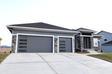 Large modern gray one-story stucco house exterior idea in Kansas City with a hip roof and a shingle roof
