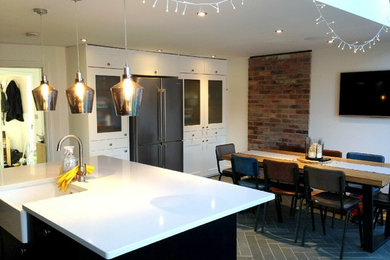 トランジショナルスタイルのおしゃれなキッチン (エプロンフロントシンク、御影石カウンター、セラミックタイルのキッチンパネル、黒い調理設備、セラミックタイルの床) の写真
