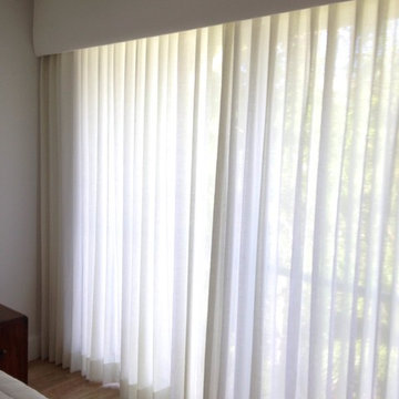 Bedroom with upholstered cornice with traversing sheer drapery