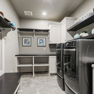 Aménagement d'une grande buanderie classique en L multi-usage avec des portes de placard blanches, un mur gris, un sol en vinyl, des machines côte à côte, un sol gris et un placard à porte shaker.