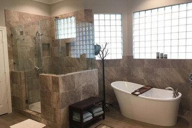 This is an example of a transitional master bathroom in Houston with a freestanding tub and a hinged shower door.