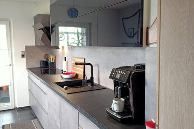 Geschlossene, Einzeilige Moderne Küche mit Einbauwaschbecken und schwarzen Elektrogeräten in Sonstige