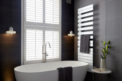 Large contemporary ensuite bathroom in Kent with flat-panel cabinets, white cabinets, a freestanding bath, a walk-in shower, a wall mounted toilet, grey tiles, porcelain tiles, white walls, porcelain flooring, a vessel sink, brown floors and an open shower.