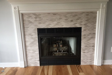 グランドラピッズにある小さなトラディショナルスタイルのおしゃれなリビング (グレーの壁、無垢フローリング、標準型暖炉、タイルの暖炉まわり、テレビなし、茶色い床) の写真