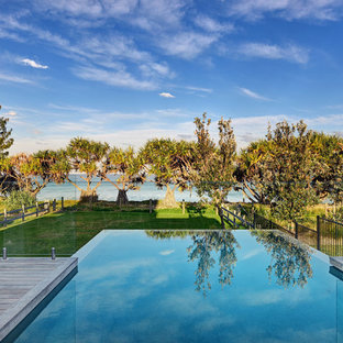 Tropischer Infinity-Pool hinter dem Haus in rechteckiger Form mit Dielen in Sonstige