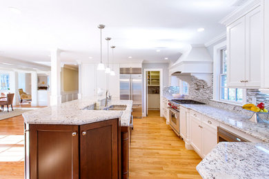 This is an example of a large contemporary l-shaped open plan kitchen in Boston with an undermount sink, recessed-panel cabinets, white cabinets, granite benchtops, multi-coloured splashback, matchstick tile splashback, stainless steel appliances, medium hardwood floors, with island and brown floor.