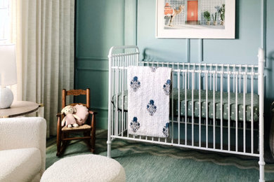 Imagen de habitación de bebé costera pequeña con paredes azules, moqueta, suelo beige y panelado