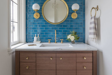 Example of a transitional blue tile and subway tile black floor powder room design in Portland with flat-panel cabinets, dark wood cabinets, white walls, an undermount sink and white countertops