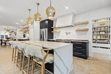 Kitchen pantry - large modern galley light wood floor and brown floor kitchen pantry idea in New York with an undermount sink, shaker cabinets, black cabinets, quartzite countertops, white backsplash, ceramic backsplash, stainless steel appliances, an island and white countertops