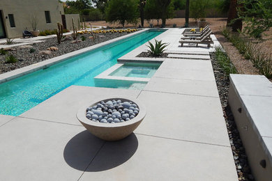 Foto de piscinas y jacuzzis alargados contemporáneos grandes a medida en patio trasero con losas de hormigón