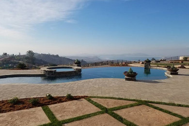 Inspiration for a mid-sized timeless backyard concrete paver and custom-shaped infinity hot tub remodel in Los Angeles