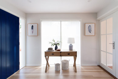 Inspiration pour un hall d'entrée traditionnel de taille moyenne avec un mur blanc, parquet clair, une porte simple et une porte bleue.