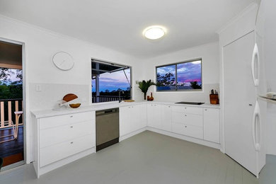 Small modern l-shaped kitchen in Brisbane with white cabinets, laminate benchtops, beige splashback, ceramic splashback, black appliances and light hardwood floors.
