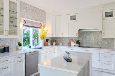 Photo of a mid-sized transitional u-shaped eat-in kitchen in Vancouver with an undermount sink, shaker cabinets, white cabinets, quartz benchtops, grey splashback, mosaic tile splashback, stainless steel appliances, vinyl floors, with island, grey floor and white benchtop.