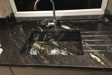 Immagine di una grande cucina ad U minimal chiusa con lavello integrato, top in granito, paraspruzzi nero, paraspruzzi in lastra di pietra e top nero