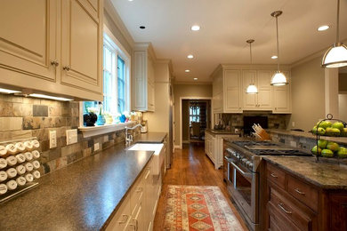 Large elegant galley medium tone wood floor and brown floor eat-in kitchen photo in Birmingham with a farmhouse sink, raised-panel cabinets, yellow cabinets, multicolored backsplash, stone tile backsplash and stainless steel appliances