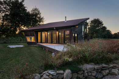 Small black two-story wood exterior home idea in Providence with a shed roof and a metal roof
